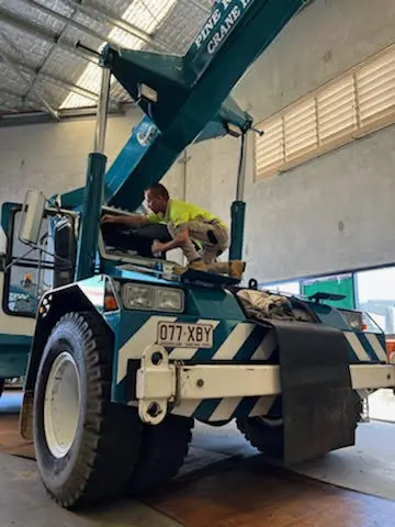 Technician working on the cab of a mobile crane in a workshop