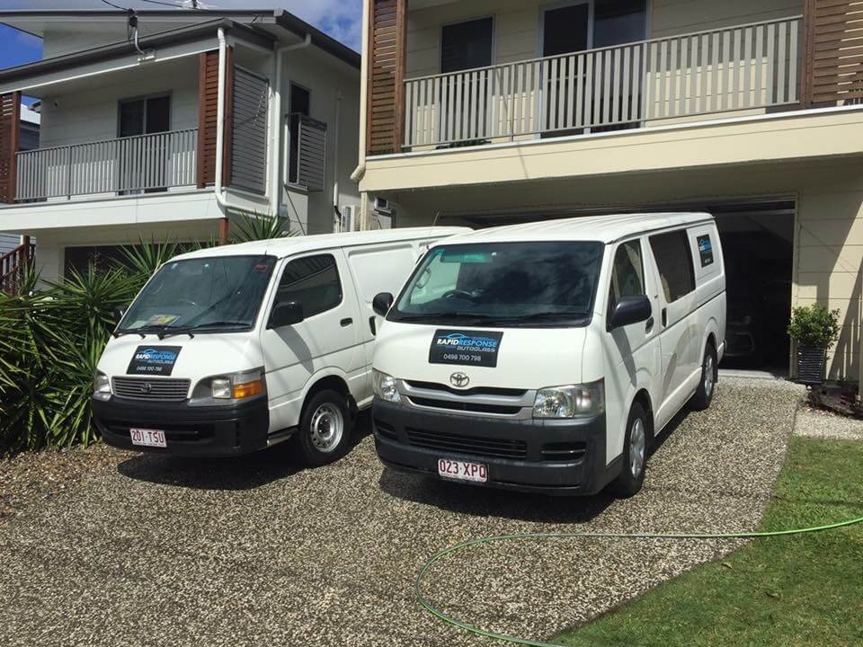 Two Rapid Response Autoglass vans parked at a house